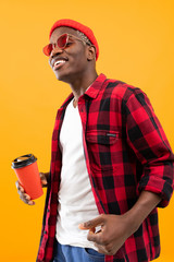 portrait of a black american man dressed stylishly holding a drink glass on a coffee break yellow background