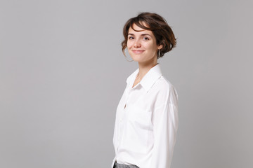 Side view of smiling cute young business woman in white shirt posing isolated on grey wall...