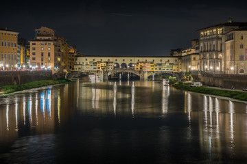 Fototapeta na wymiar Ponte Vecchio in historical center downtown in Florence during sunrise with water reflections in Arno river