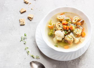 Vegetable soup with egg pancakes on light grey background. Traditional German Flaedlesuppe and Austrian Frittatensuppe. 
