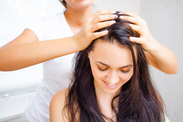 Masseur makes head massage to a young brunette woman. Head massage close up.