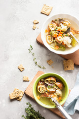 Vegetable soup with egg pancakes on light grey background. Traditional German Flaedlesuppe and Austrian Frittatensuppe. 