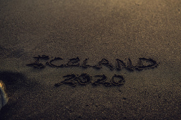 Iceland 2020. inscription in the sand. Text on black sand beach in Iceland. Europe travel destination. Icelandic landscape background.