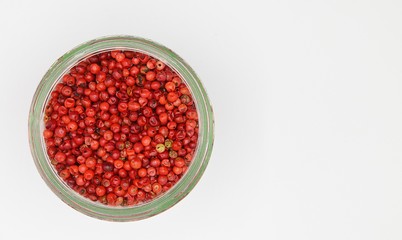 Top view on opening of isolated glass jar with red pepper corns and white blank empty background