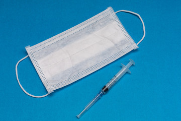 White medical mask and disposable syringe. Medical supplies.