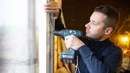 Installation of a plastic window. Worker using screwdriver. Renovation at home. Building construction indoor. ..