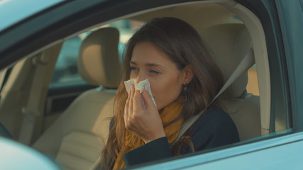 Sick young woman sitting in car sneeze holds a handkerchief vehicle influenza health illness flu medical sickness problem business infection headache slow motion