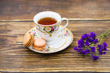 Cup of tea with macaroons on wooden background