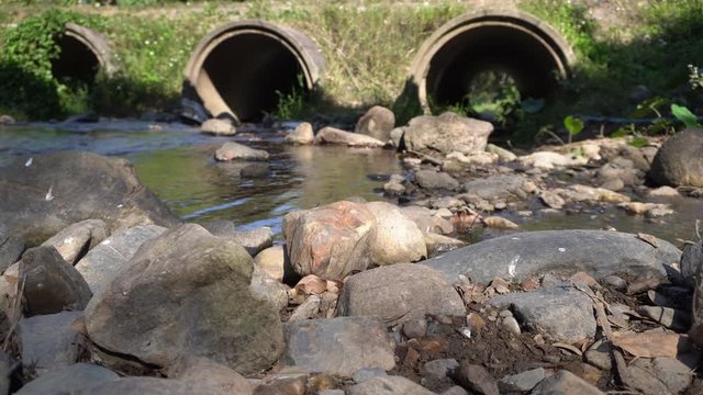 Reinforced concrete box culverts under the road with waterfall. Box culvert is a structure that allows water to flow under a road. 