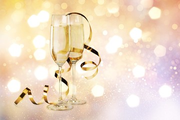 Glasses of champagne with curly ribbon on desk