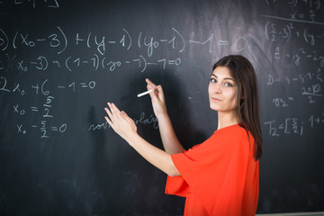 Pretty, young college student writing on the chalkboard/blackboard during a math class