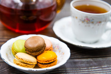 Cup of tea with macaroons on wooden background