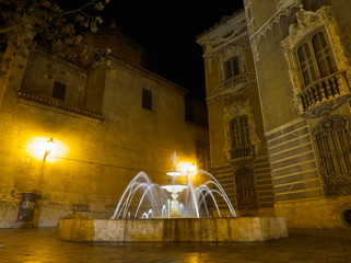 Water fountain and beautiful facade by night in Valencia