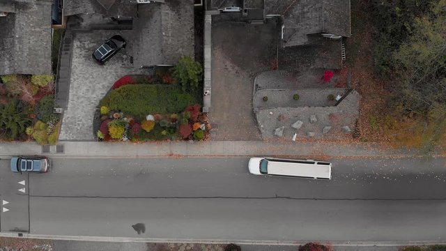 A white SUV limosine pulls up outside a house in an affulent neighborhood to pick up a woman waiting outside. 4K 24FPS.