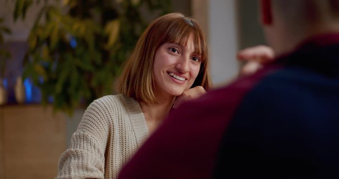 Close up of beautiful female smiling while communicating with best friends at dinner, happy young ginger Hispanic girl in good mood enjoying conversation with family dressed in stylish cute outfit