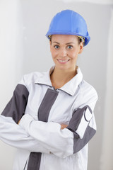 smiling woman wearing builder helmet standing with crossed arms
