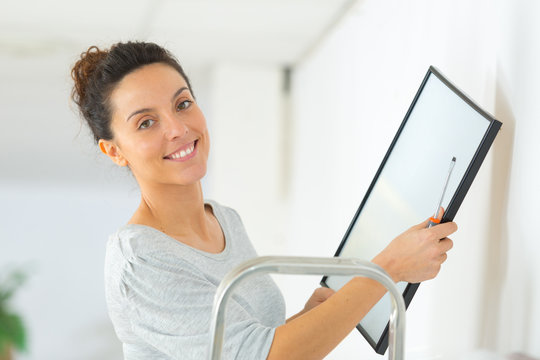 woman hanging empty picture frame at her new home