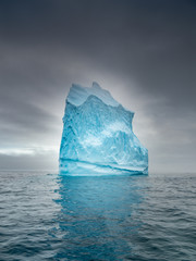 alone iceberg under clouds