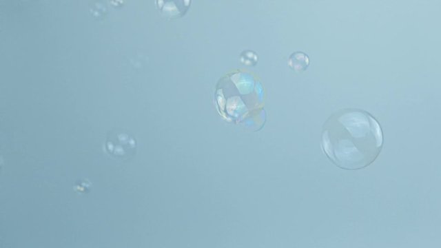 Video footage of slow motion soap bubbles on a grey background.
