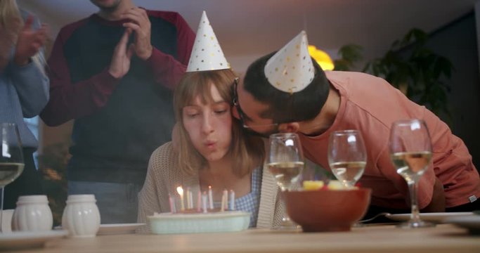 Funny young Hispanic man congratulating girlfriend and friends clapping hands at home, nice ginger girl smiling feeling happy in cute cozy atmosphere and white wine glasses on kitchen table evening