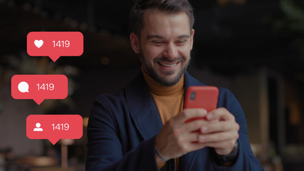 Happy young man in shopping mall with Christmas gifts in hand uses smartphone typing social media icons with like comment follower counter quick increase blogger influencer internet blog slow motion