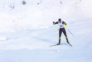 A man cross-country skiing on trail. Guy with modern ski equipment and race number - obrazy, fototapety, plakaty