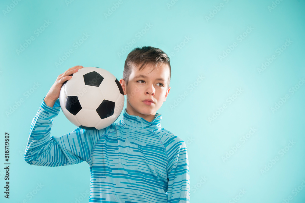 Wall mural Boy posing with soccer ball on blue studio background.