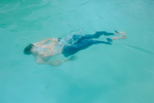 Man floating in blue water in pool during the summer 