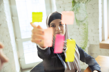 Organizing tasks. Portrait of a beautiful arabian businesswoman wearing hijab while working at openspace or office. Concept of occupation, freedom in business area, leadership, success, modern