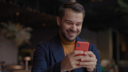 Close up smiling young man in shopping mall with Christmas gifts in hand uses smartphone typing social media icons with like comment follower counter quick increase blogger influencer blog slow motion
