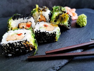 Traditional sushi with tuna and seaweed on a black plate. Japanese style food, close up. 