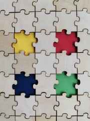Fototapeta premium Wooden puzzles background with four different color puzzles piece. World Autism awareness concept.