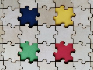 Wooden puzzles background with four different color puzzles piece. World Autism awareness concept.