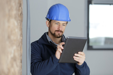 man builde uses a tablet in site