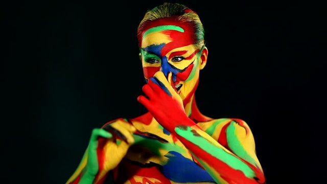 Woman dancing with color face art and body paint. Colorful portrait of the girl with bright make-up and bodyart.