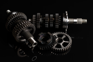 Racing motorcycle gearbox transmission on a black reflective background. 