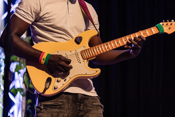 Closeup of african professional male musician wearing white t-shirt and playing electric guitar on...