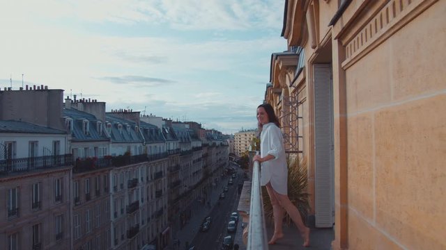 Beautiful girl in a white shirt on the balcony in the morning