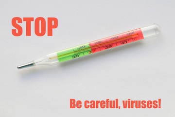 Glass thermometer on a light background and words in red letters: STOP. Be careful, viruses! Selective focus.
