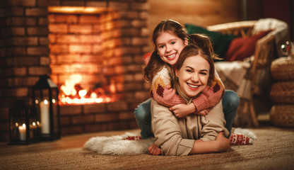 Fototapeta na wymiar family mother and child reading book and drink tea on winter evening by fireplace