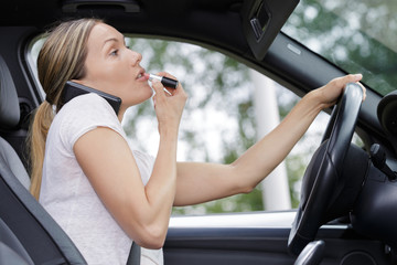 Naklejka premium woman applying makeup while driving her car