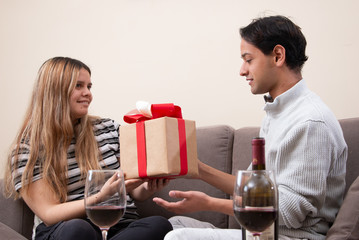 Cute young latin couple exchanging gift for valentines day