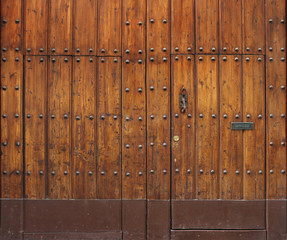 ancient and worn wooden gate with rivets and two small doors