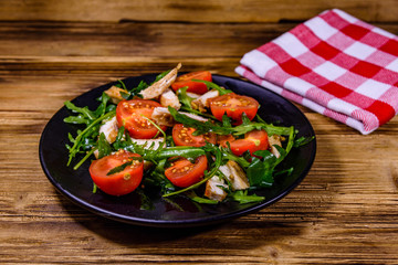 Roasted chicken breasts and salad with arugula and cherry tomatoes in a black plate