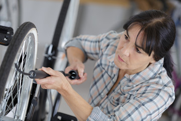 woman pumping-up a bike tire using small pump