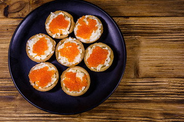 Tartlets with red caviar on a black plate. Festive food. Top view