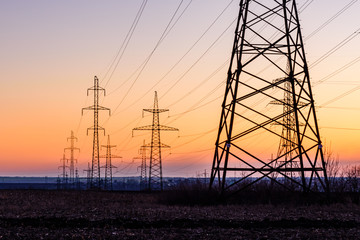 High voltage power line in a field at sunset