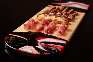 Exclusive painted art cutting board made of wood organic serving dishes with taste food cuisine delicious snack meat jerky bread dried cheese.