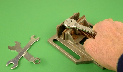 Lavoro manuale, attrezzi per le attività meccaniche: mano che stringe un bullone con una chiave...
