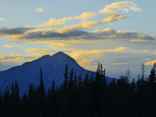 Gold and orange sunset reflected in clouds over a mountain peak